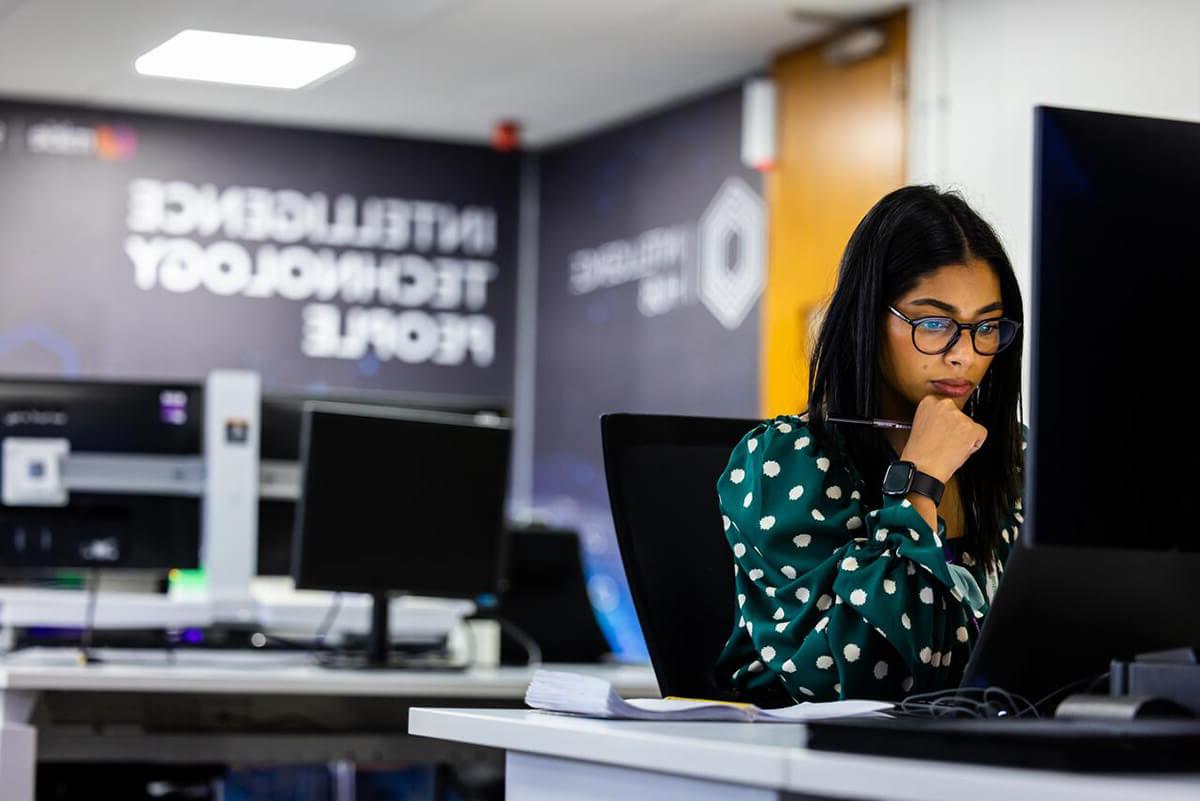 Woman in glasses working at a computer in the Mitie Intelligence Hub